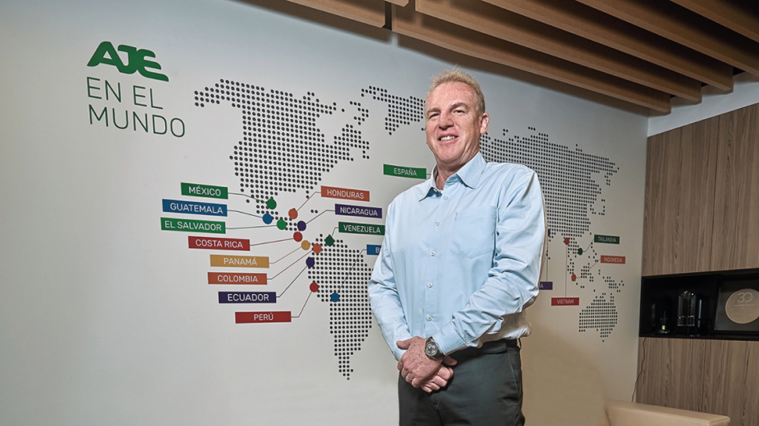 Representante de AJE junto al mapa de presencia global